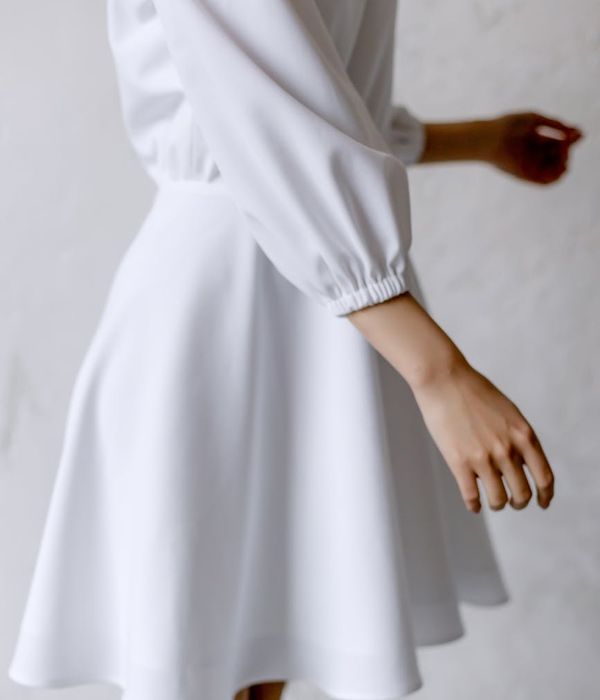 Woman in a calm, flowing movement pose in a bright, airy room.